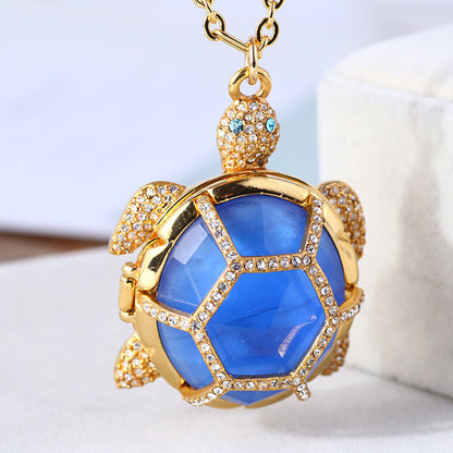 A gold colored closed pedant with a blue turtle shell 