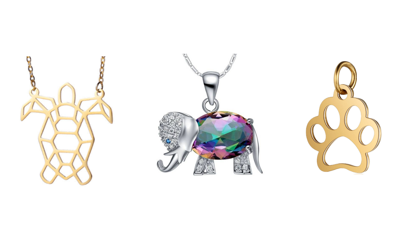 A gold turtle necklace, silver elephant necklace and gold paw charm next to each other on a white background