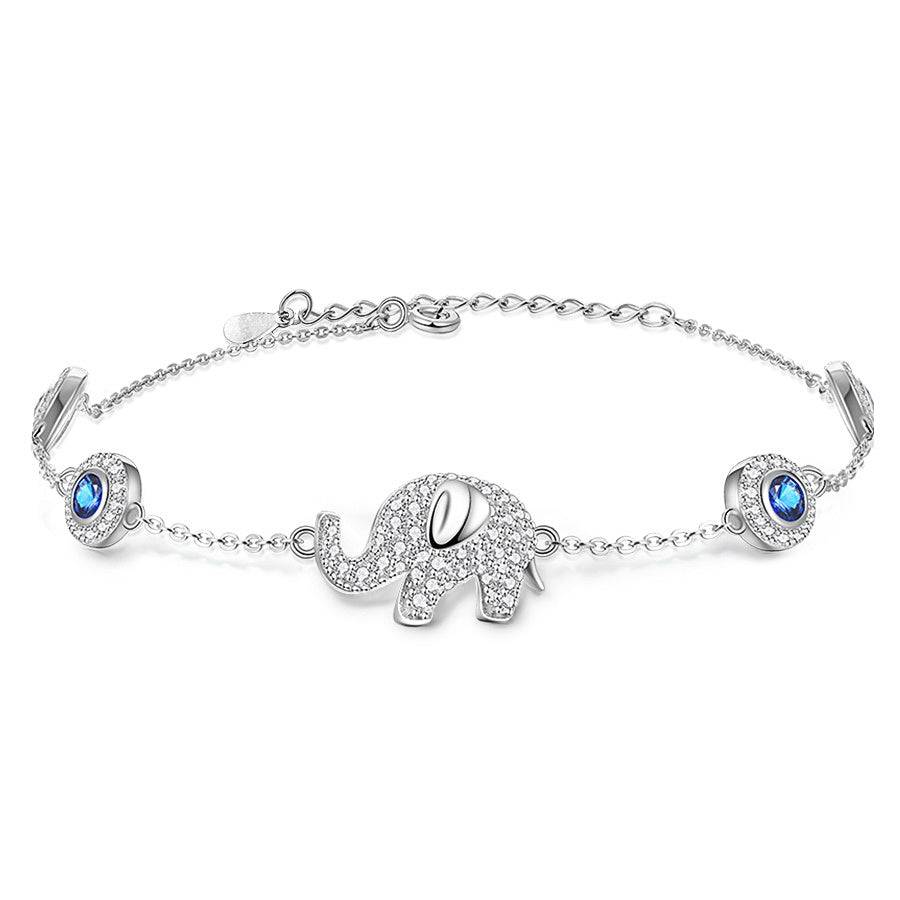 A silver bracelet laid down with an elephant pendant on it