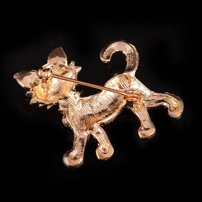 The reverse side of a gold cat brooch on a black background.