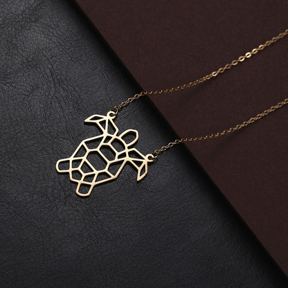 A gold necklace with a turtle pendant laid out on a leather book