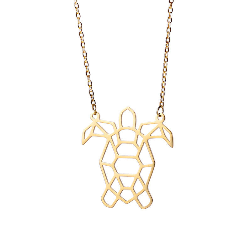 A gold colored turtle necklace on a white background 